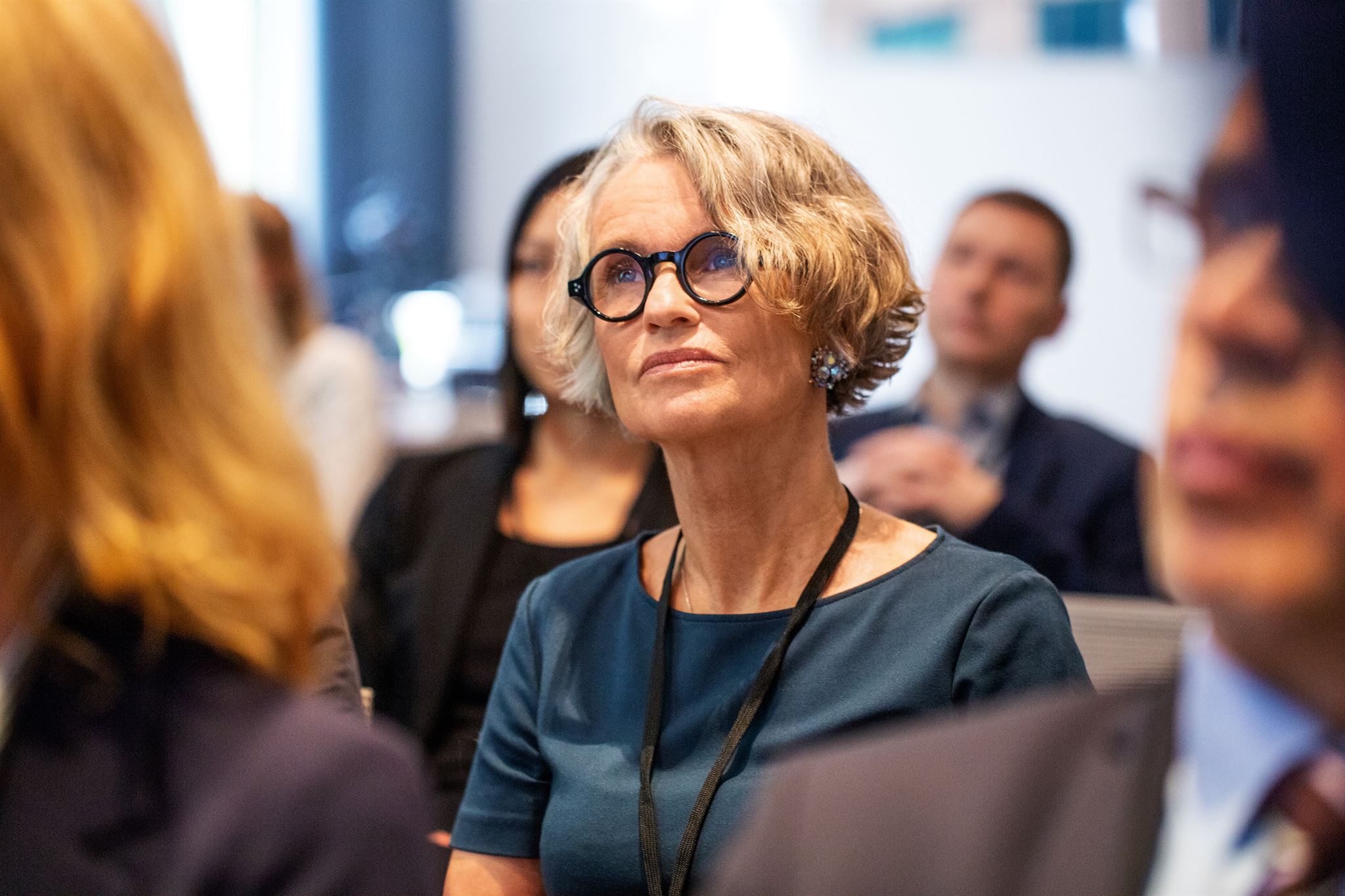 Rows-of-seated-people-in-business-attire,-listening-to-work-event